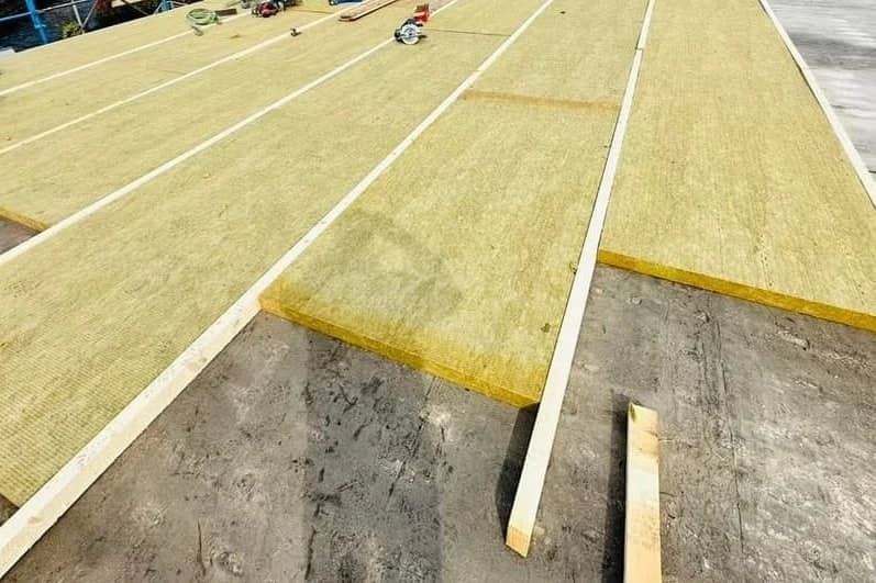 Pannelli isolanti gialli stesi sul tetto, tra listelli di legno.