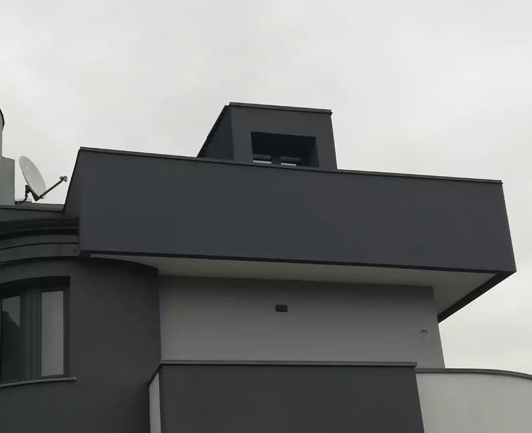 Dal basso, i volumi in cima alla casa: il volume grigio scuro che sporge sopra l’intradosso bianco, con la copertina antracite sul bordo; sopra, il torrino con la finestra e la sua copertina; a sinistra la cornice curva del bovindo; sotto, il parapetto scuro del terrazzo con la copertina e, a destra, quello bianco che gira in curva, con la sua.