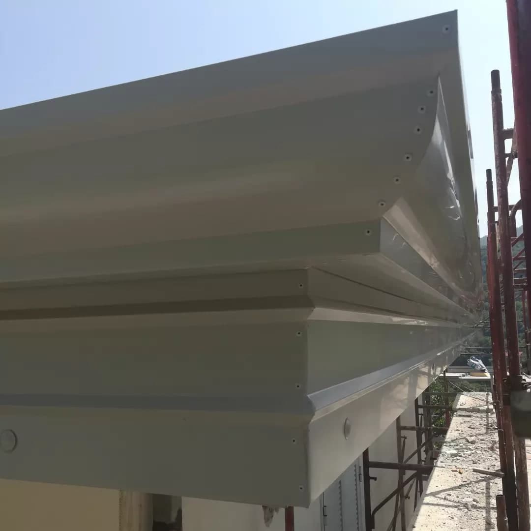 Dal ponteggio, il profilo della gronda a cornice bianca: in alto la pancia tonda con i rivetti, sotto la cornice a gradini con la fascia grande.