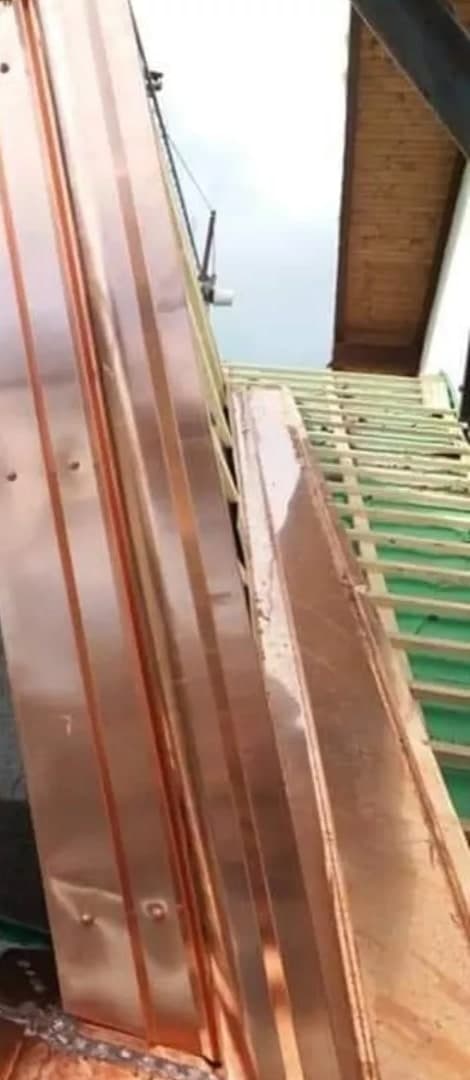Un altro lavoro dello stesso post, a lavoro in corso: il fianco di un abbaino rivestito di lastre di rame verticali, con le viti, e la lamiera di rame che scende lungo il bordo del tetto; a destra la falda con i listelli e il sottogronda di legno.