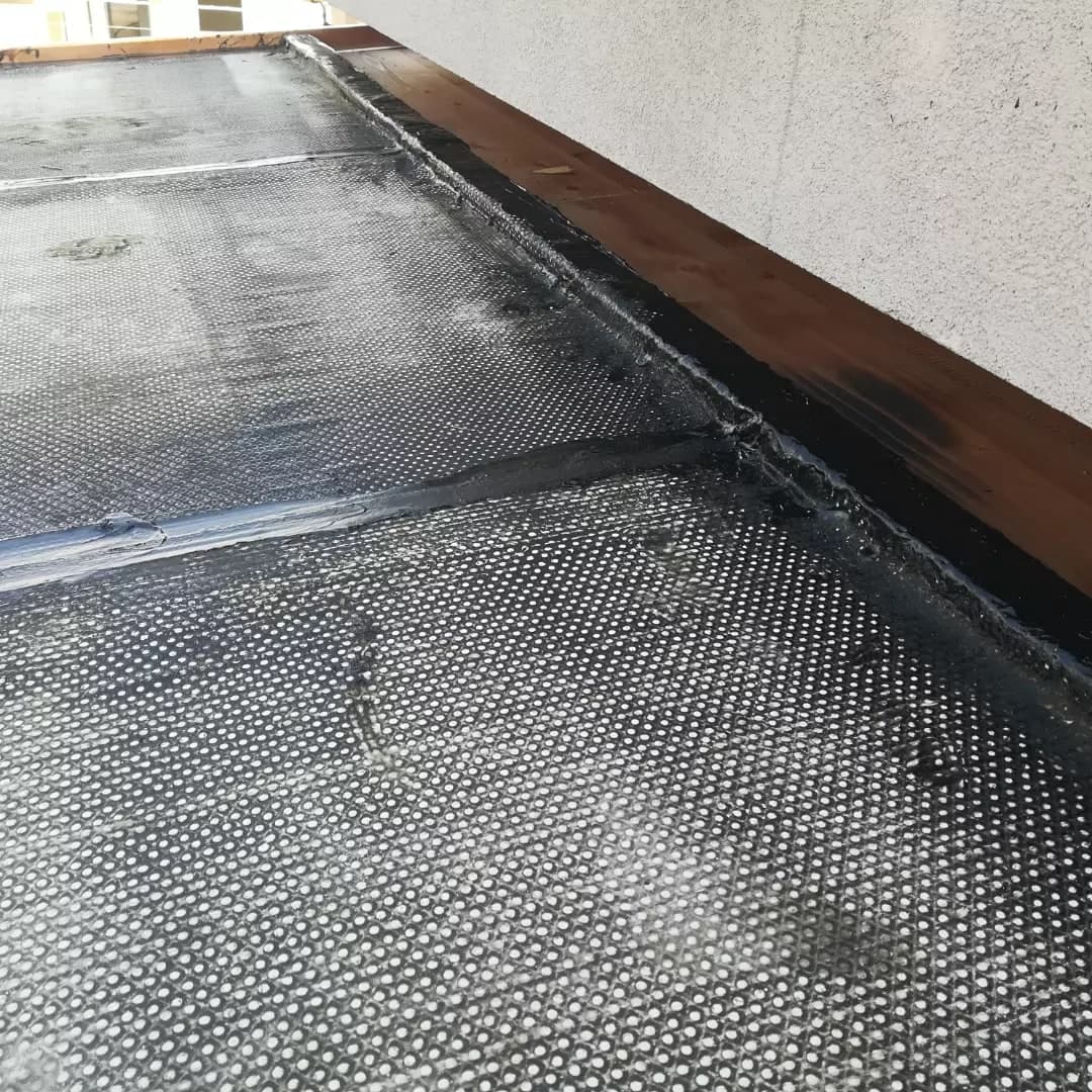 Durante il lavoro: il primo strato di guaina steso a teli sul tavolato, risvoltato sulla tavola di legno fissata lungo il muro.